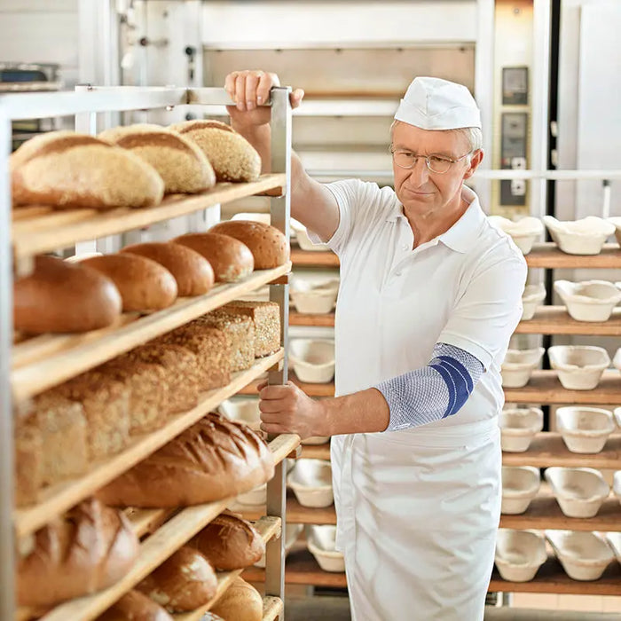 A man wearing the EpiTrain Elbow Brace while working in a bakery.