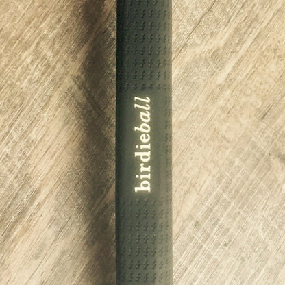 A close-up of a black BirdieBall grip with "birdieball" printed on it, placed on light wood, ideal for the American Classic Putter (Anser Style + Milled Face + Heel/Toe Weighted).