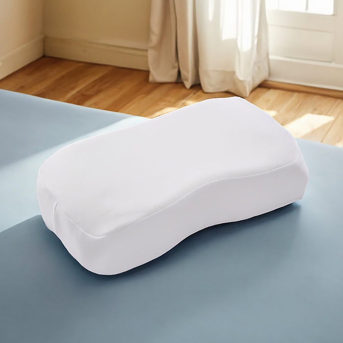 White ergonomic pillow on a bed with a window in the background