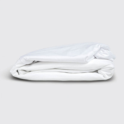 Folded white mattress protector on a light gray background