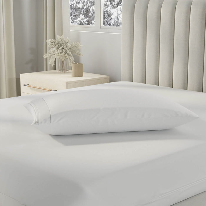 White pillow on a bed in a bedroom with a window and desk in the background
