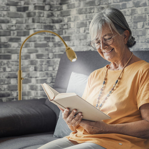 Woman using the FOCUS Adjustable Beam Floor Lamp in gold