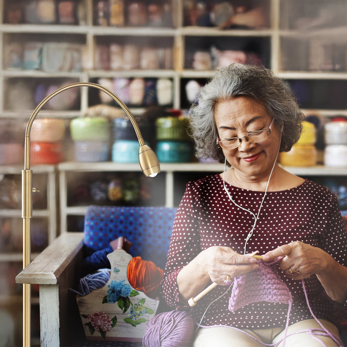 Woman using the FOCUS Adjustable Beam Floor Lamp to crochet