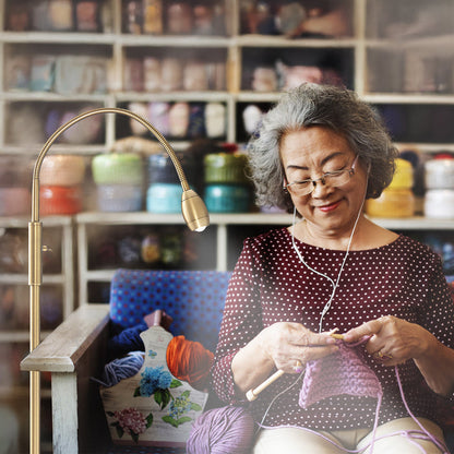 Woman using the FOCUS Adjustable Beam Floor Lamp to crochet