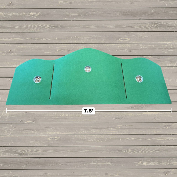 The BirdieBall Full Width Hole Deepening/Break Shim (For Use with Turf Mats) is a green, curved panel featuring Tour Grade Turf, three round vents, and two vertical slits, measuring 7.5 feet wide on a wooden floor background.