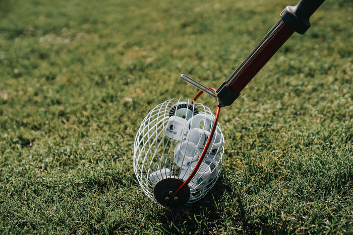A close-up of the BirdieBall Golf Ball Picker Upper - Shag Wheel, a super fast and easy ball picker, filled with BirdieBalls for backyard golf practice, resting on grass.