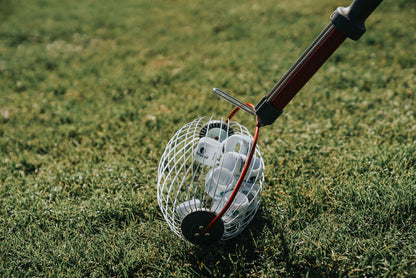 A close-up of the BirdieBall Golf Ball Picker Upper - Shag Wheel, a super fast and easy ball picker, filled with BirdieBalls for backyard golf practice, resting on grass.