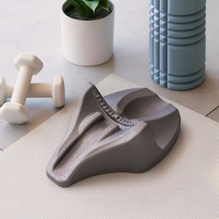 Gray wedge-shaped decompression device on a light surface with a plant and container in the background