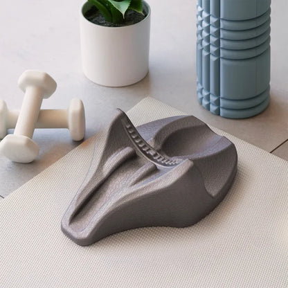 Gray wedge-shaped decompression device on a light surface with a plant and container in the background