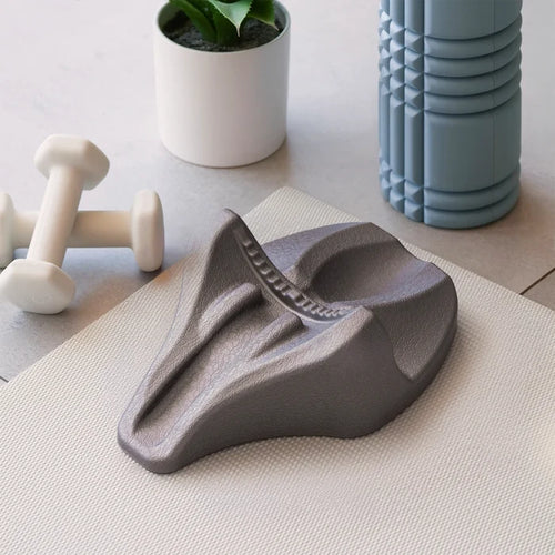 Gray wedge-shaped decompression device on a light surface with a plant and container in the background