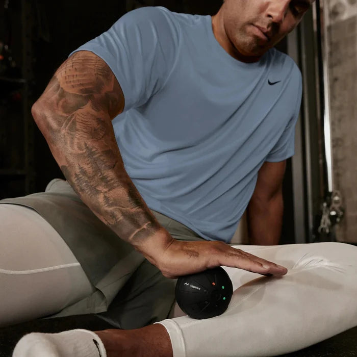Man using a massage ball on his leg in a home setting