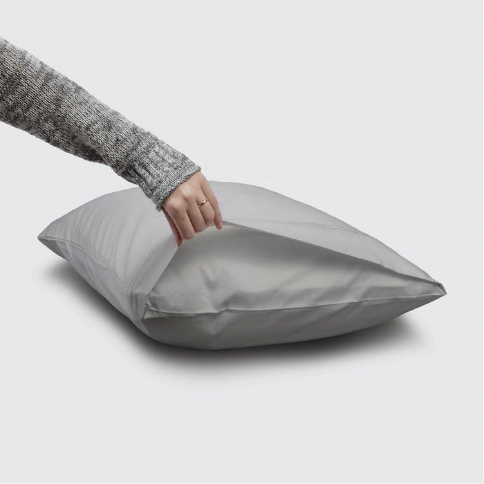 Person holding a gray satin pillowcase on a light gray background
