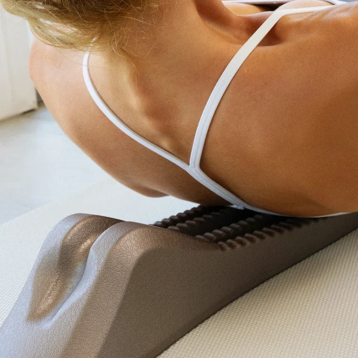 Woman using a gray spine decompression stretcher on her back