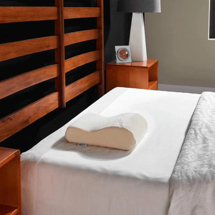 TEMPUR-Neck Travel Pillow sitting on top of a bed in a bedroom setting.