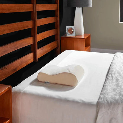 TEMPUR-Neck Travel Pillow sitting on top of a bed in a bedroom setting.