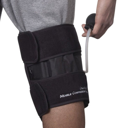 A person wearing a black knee support brace with a hand holding a small black pump connected by a clear tube, against a white background.