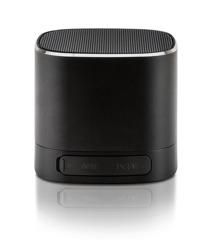 A black cylindrical portable speaker with a power button panel on the front, shown on a reflective white surface.