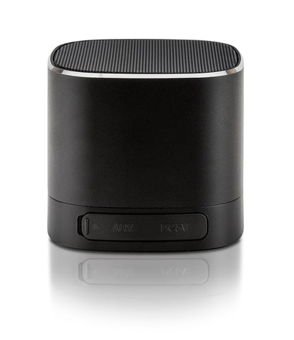 A black cylindrical portable speaker with a power button panel on the front, shown on a reflective white surface.