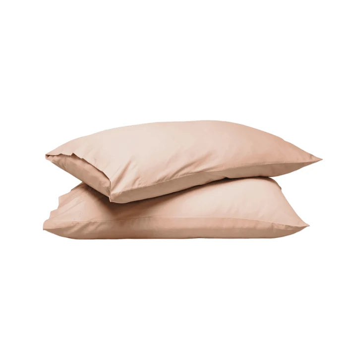Two plain pillowcases stacked on a white background, in a soft warm beige or blush-tan tone.